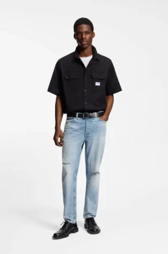 Blå jeans med avsmalnande passform i slitna denim